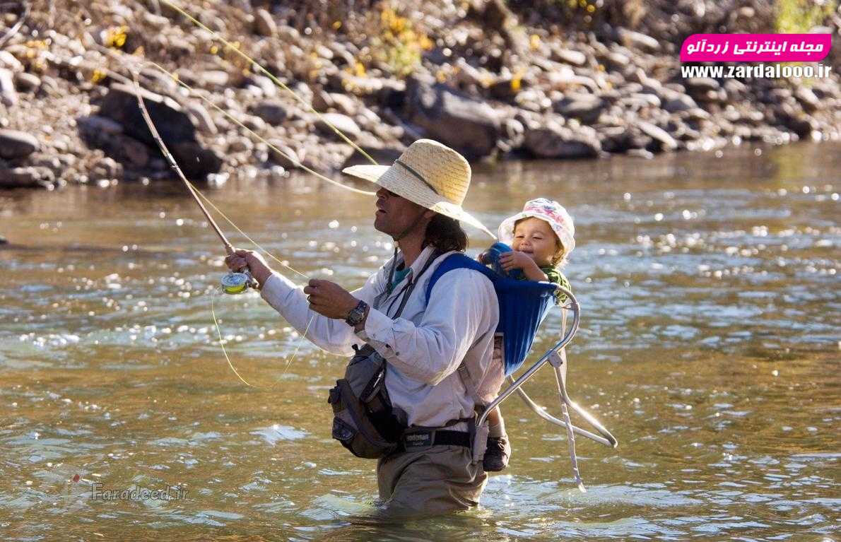 پسربچه‌ای پشت پدرش که در حال ماهیگیری در رودخانه دولورس در کلرادو است.