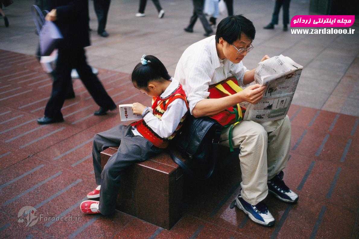 پدر و دختر غرق در مطالعه در خیابان شلوغی در شانگهای